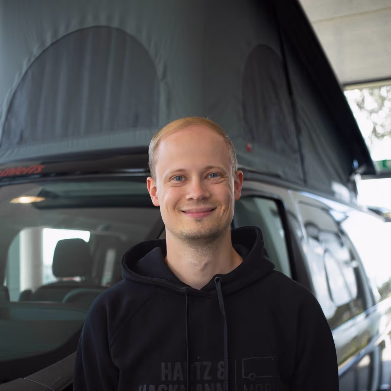 Jan-Niklas Wienhold-Vermietung Jan-Niklas Wienhold von Hartz & Hackmann Mobile vor einem Wohnmobil im Showroom