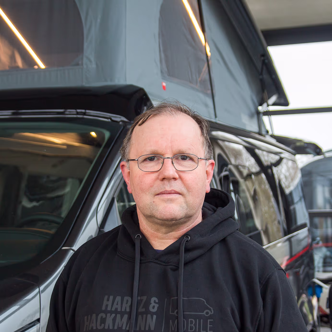 Werner Zimmermann_Mechaniker Werner Zimmermann von Hartz & Hackmann Mobile vor einem Wohnmobil im Showroom