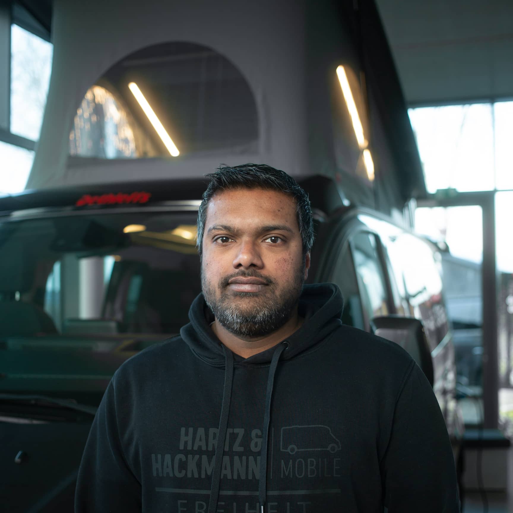Praveenan-Logeswaran-Serviceberater Serviceberater Praveenan Logeswaran von Hartz & Hackmann Mobile vor einem Wohnmobil im Showroom